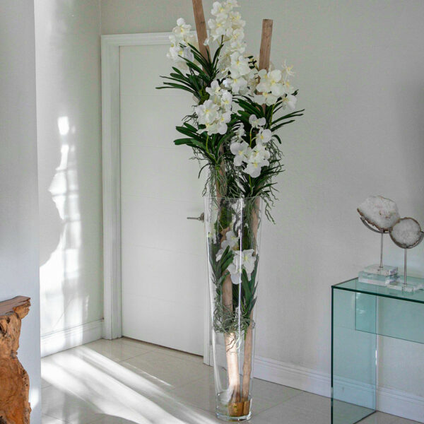 White Vanda orchids and driftwood inside large conical glass cylinder